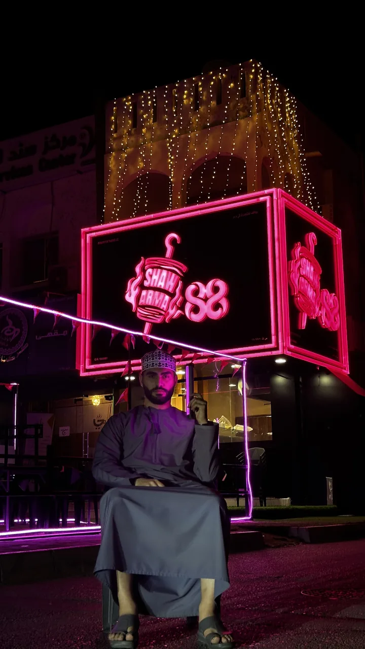 Shihab Mebarez outside Shawarma 88 at night, under its neon sign